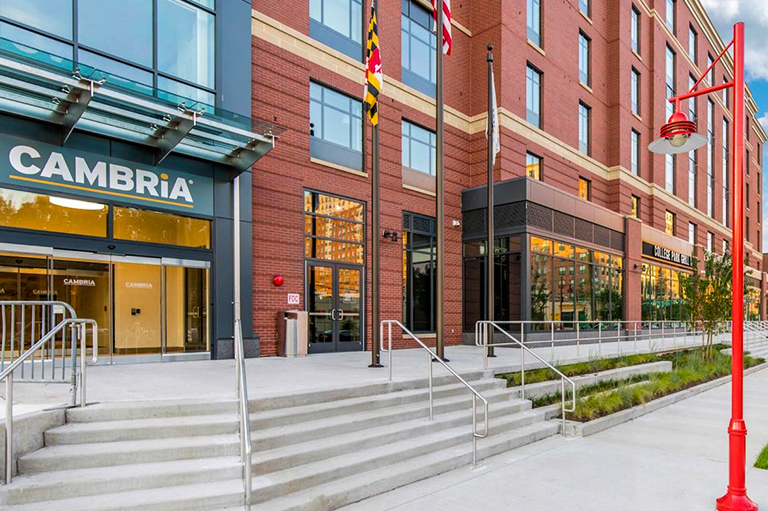 front of brick and glass building with steps leading to CAMBRIA hotel entrance